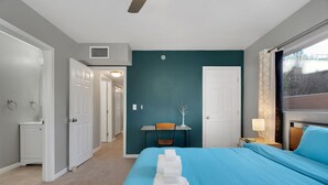 Habitación de hotel con cama, escritorio y silla. Hay toallas en la cama, una lámpara en la mesita de noche y una ventana con vistas.
