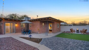 Una casa de ladrillo con un patio, mobiliario exterior y un pequeño jardín.