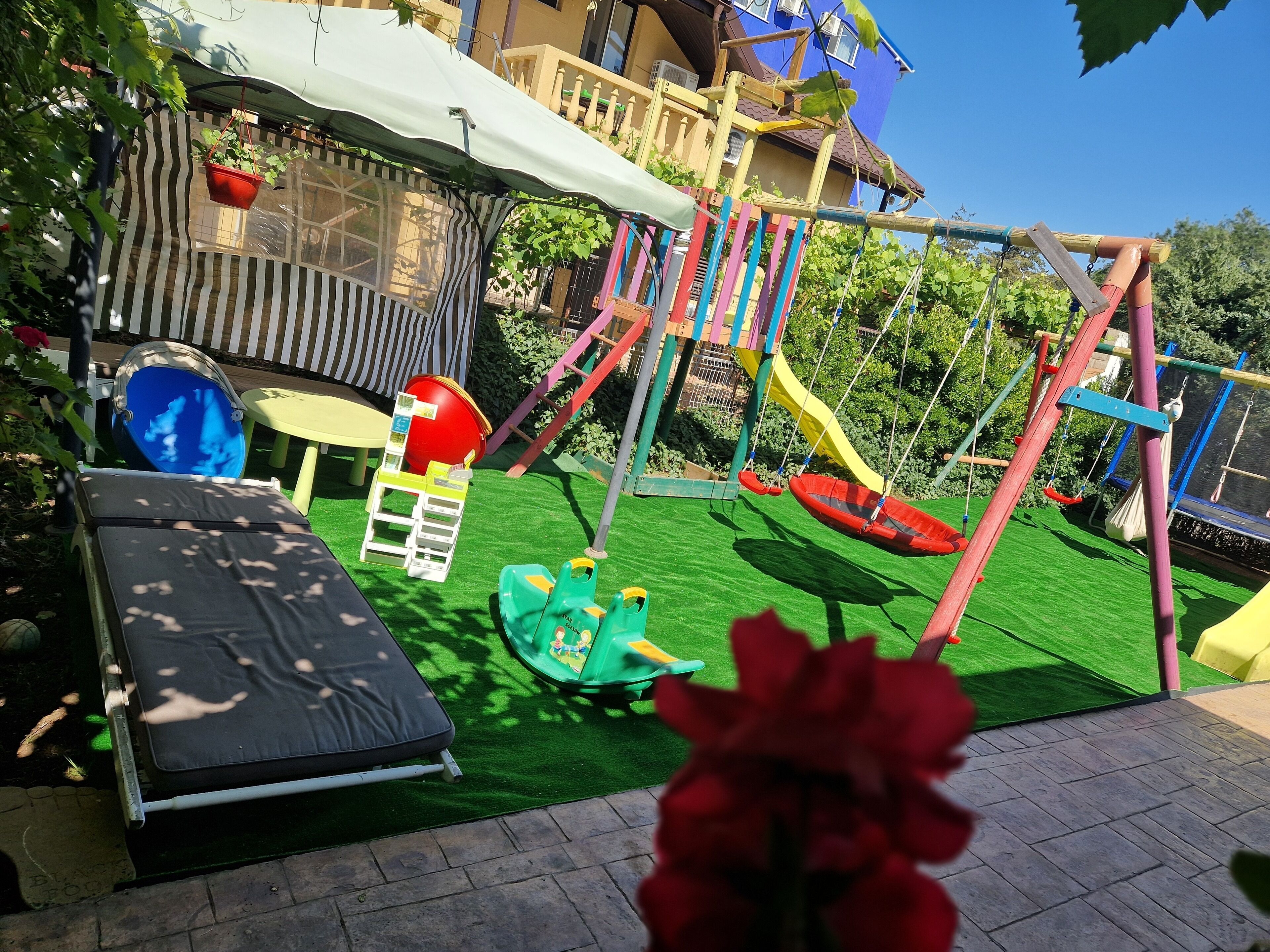 A children's play area with a slide, swings, and a small table.