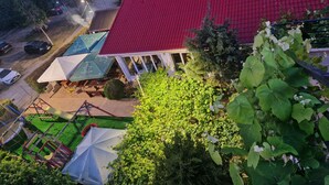 Un edificio de techo rojo con terraza al aire libre y zona cubierta con sombrillas.