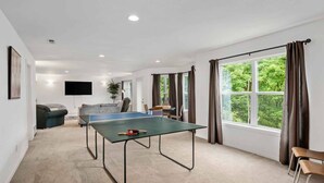 Une pièce spacieuse équipée d’une table de ping-pong, d’un canapé et d’un téléviseur.