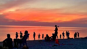 Rantamaisema, jossa ihmisiä auringonlaskun aikaan.