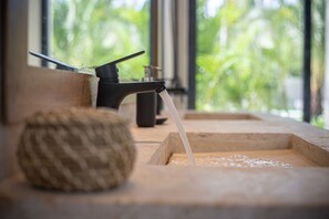 Un lavabo de madera con agua corriente, un grifo negro y una cesta tejida.