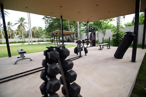 Un gimnasio al aire libre con equipo de ejercicio, una banca y un saco de boxeo.