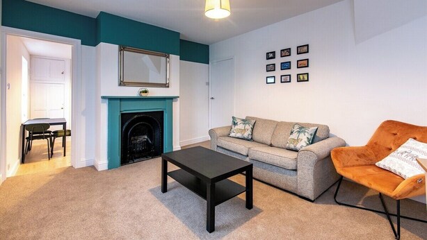 A living room with a fireplace, a sofa, a coffee table, and a chair. - Harcourt 1B: 2BR Flat with Parking in Newark (Newark-on-Trent)