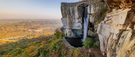 A waterfall cascading down a rocky cliff with a valley view.