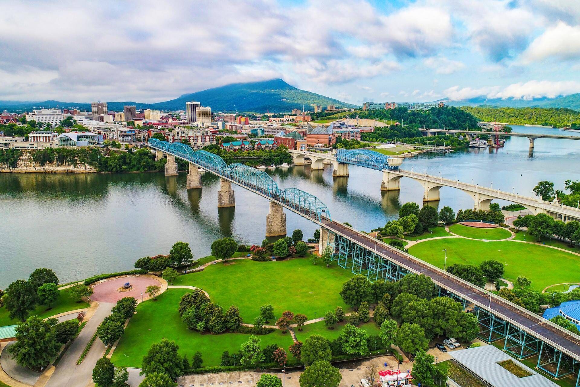 Un paisaje urbano con un puente destacado sobre un río, rodeado de vegetación y edificios.