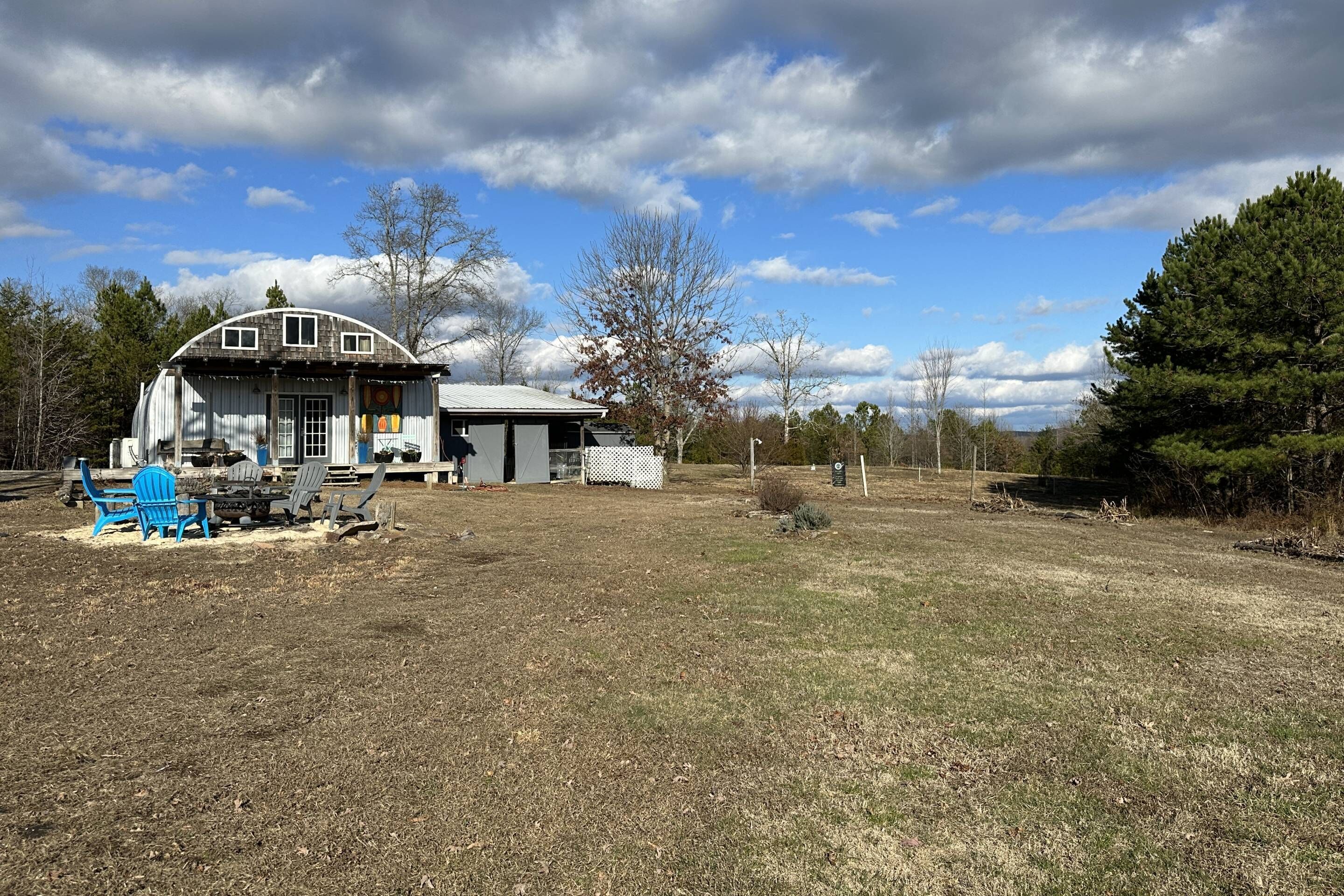 A large house with a covered porch, a small shed, and a fire pit area.
