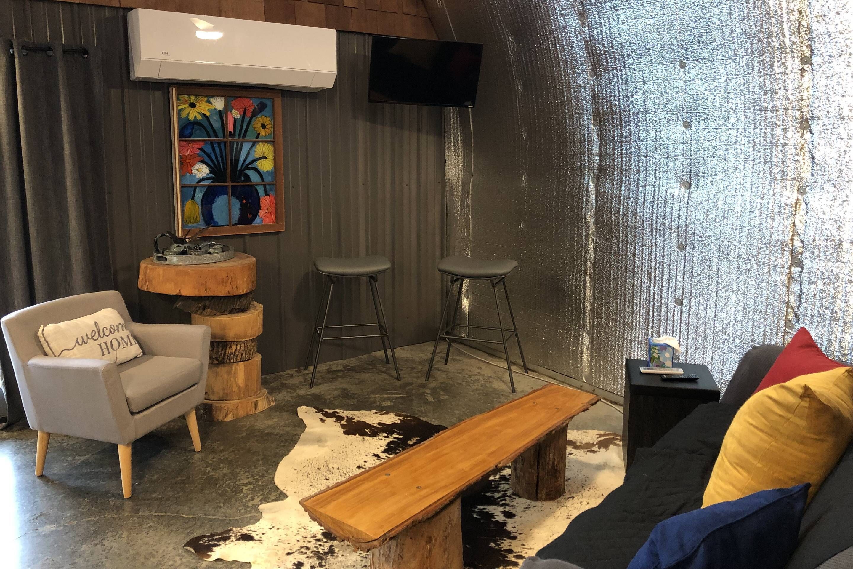 Uma sala de estar aconchegante com um sofá, um banco de madeira, uma cadeira e um banquinho.