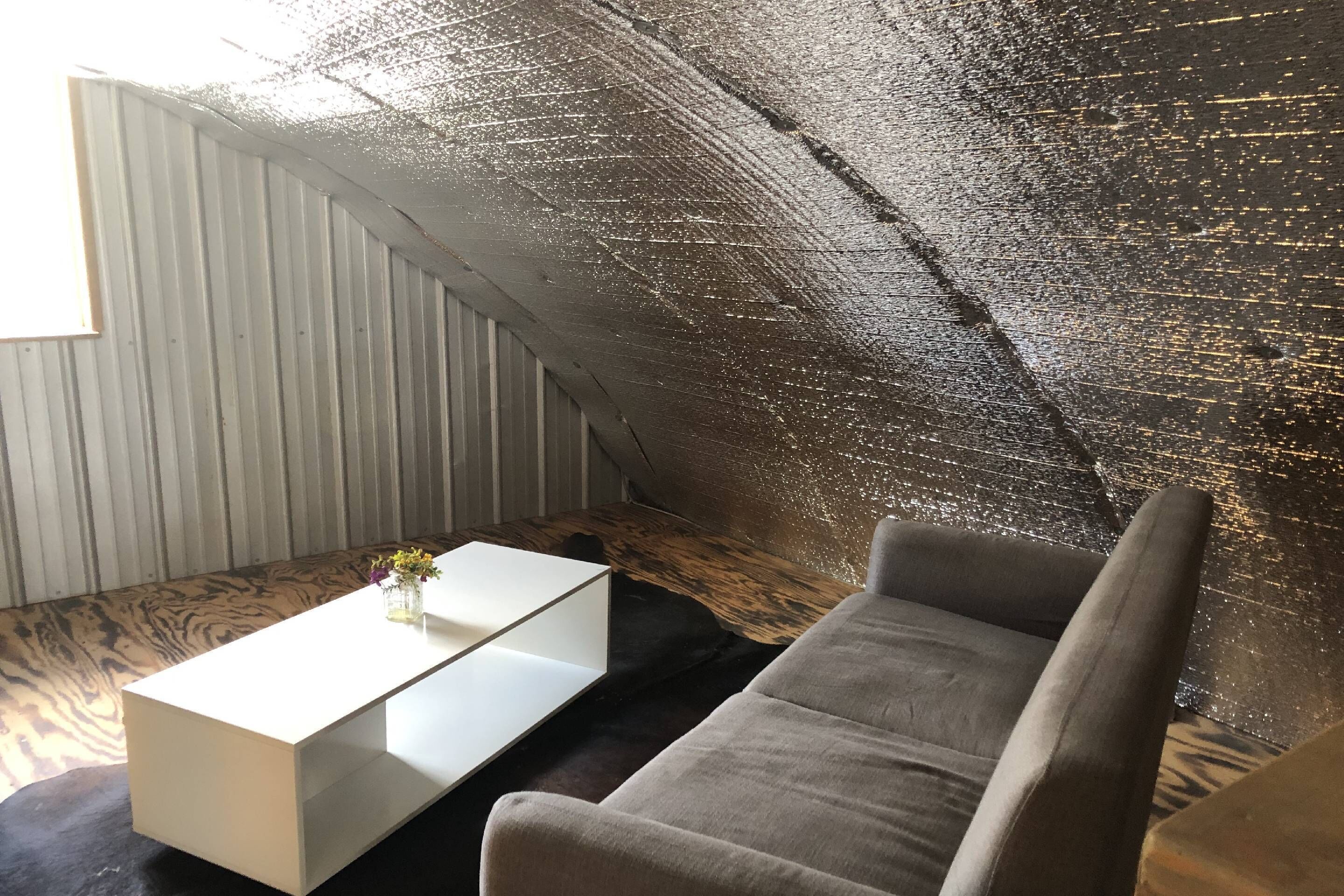 A cozy room with a curved ceiling, a white coffee table, a gray sofa, and a wooden floor.