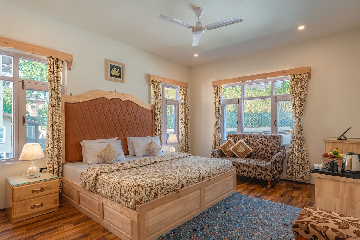 A bedroom with a wooden bed, a nightstand, a chair, and a desk with a kettle.