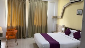 A hotel room with a bed, a chair, a desk, and curtains. - Saiba Residency (Paud)