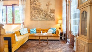 A room with a sofa, a table, a painting, and a clock.