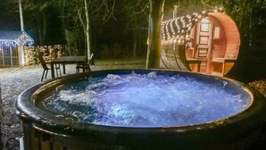 A hot tub surrounded by a wooden deck, with a small table and chairs nearby. - Spacious holiday home in the woods (Bastogne)