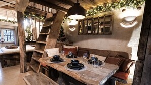A rustic dining area with a wooden table set for two, a bench, and a staircase. - Spacious holiday home in the woods (Bastogne)