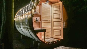 A wooden boat-shaped cabin with a door, a bench, and string lights. - Spacious holiday home in the woods (Bastogne)