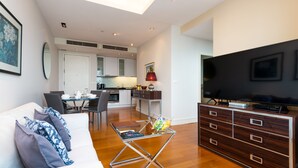 Una sala de estar moderna con un sofá, una mesa de centro, un televisor y una cocina al fondo.