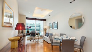 Habitación de hotel moderna con zona de comedor, un sofá, un espejo redondo y vistas de la ciudad.