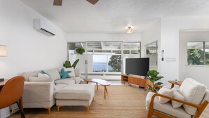 Una sala moderna con un sofá modular, un televisor y vistas al exterior.