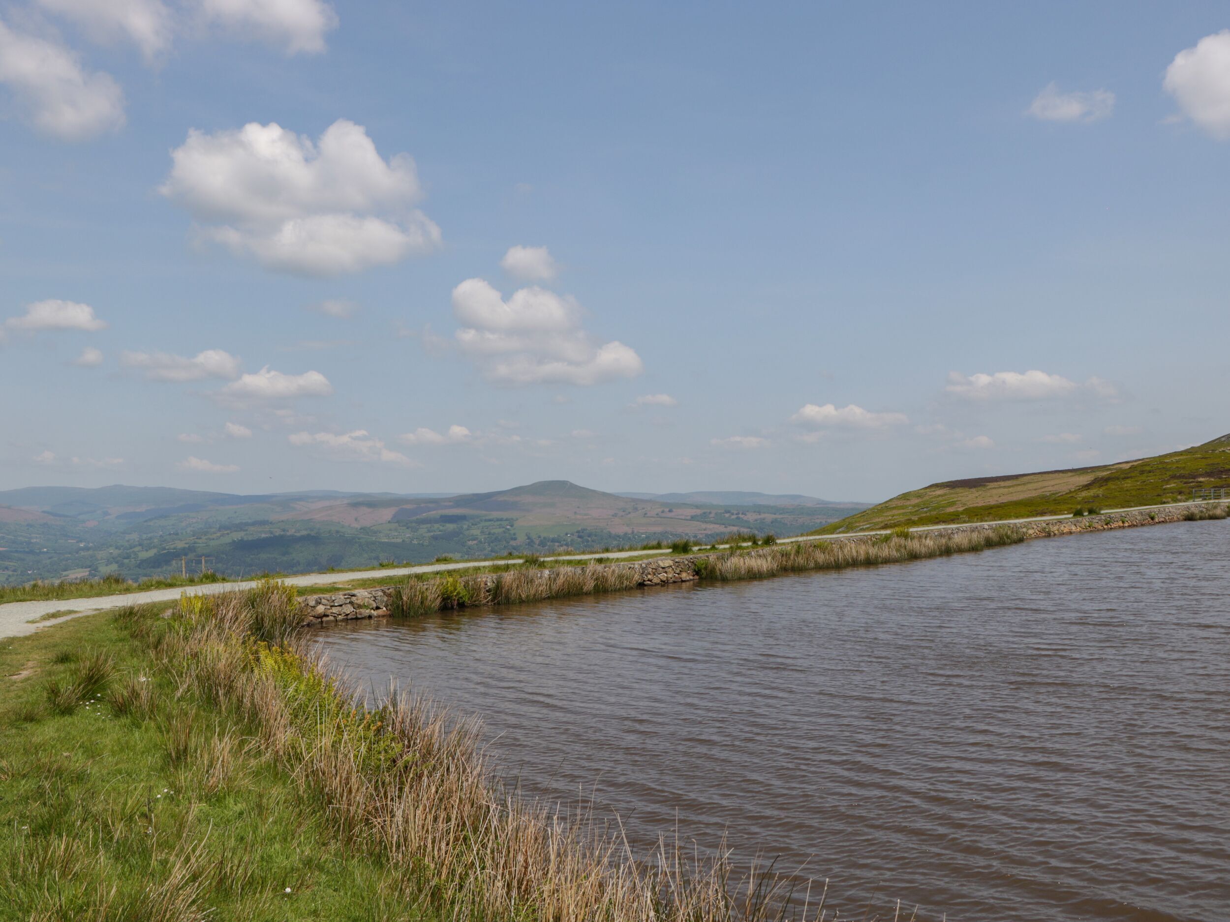 Une rivière aux rives verdoyantes, bordée de collines lointaines.