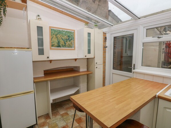 A compact kitchen with a wooden table, white cabinets, and a window with a view.