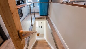 A wooden staircase leading to a kitchen with white cabinets and a blue refrigerator. - Appartement Wattside (Morsum)