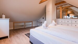 A bedroom with a large bed, a wooden bench, a desk, and a mirror. - Appartement Wattside (Morsum)