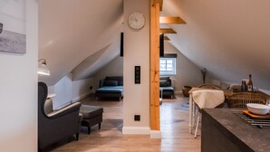 A spacious loft with a high ceiling, a wooden beam structure, a dining area with a table and chairs, and a cozy seating area with sofas and a rug. - Appartement Wattside (Morsum)