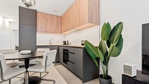 Une cuisine moderne avec un coin repas, comprenant un îlot central, une plante en pot et un four encastré.