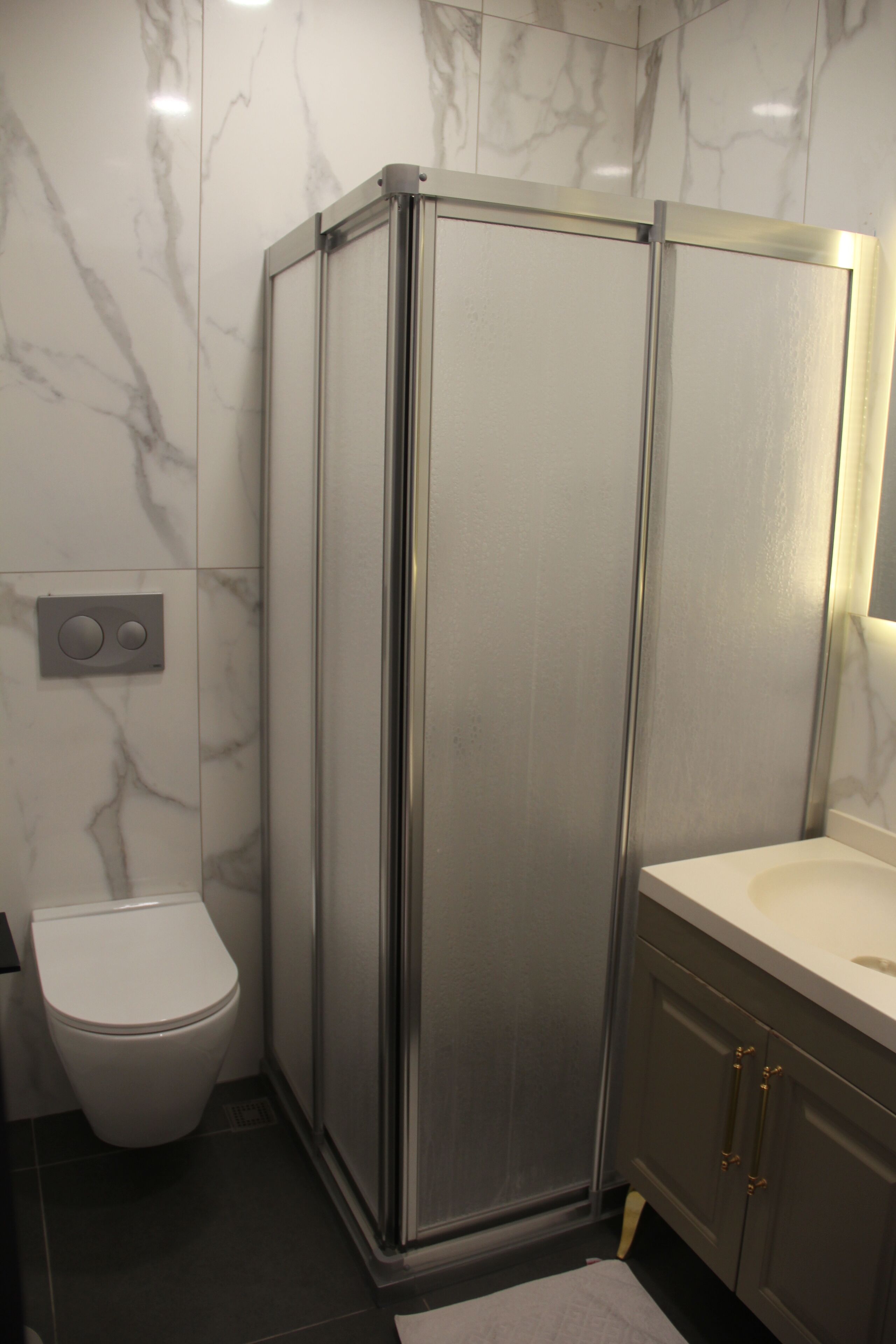 Un baño con cabina de ducha, inodoro y tocador.