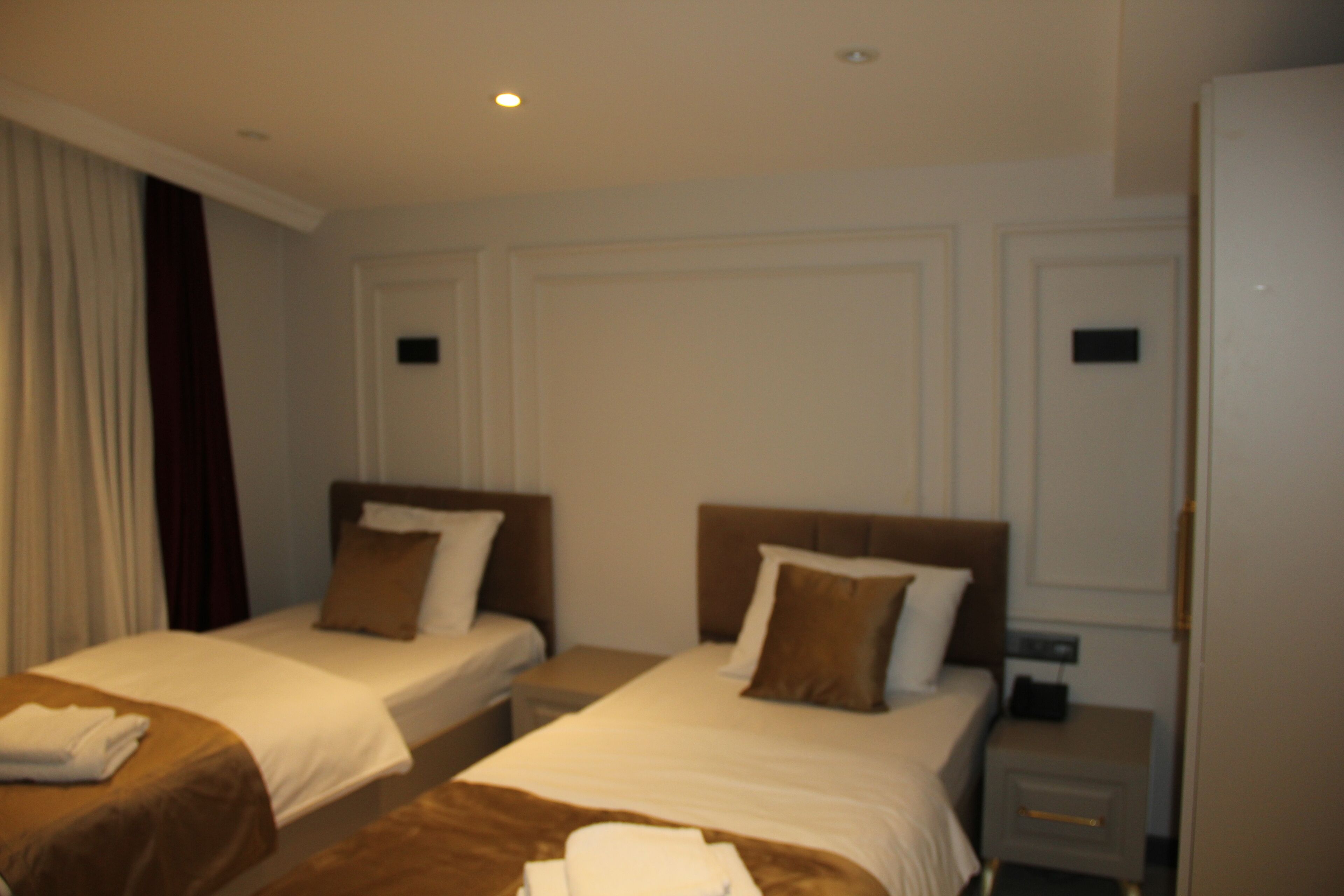 Una habitación de hotel con dos camas individuales, una mesita de noche y un armario.