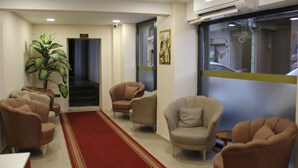 A hotel lobby with a red carpet, beige armchairs, a potted plant, and a large window with a view of the street. - EyüpSultan Palace Hotel (Eyup)
