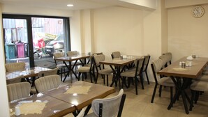 A dining area with multiple tables and chairs, a clock on the wall, and a view of the street outside. - EyüpSultan Palace Hotel (Eyup)