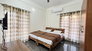 Un dormitorio con cama de madera, ropa de cama blanca y cortinas estampadas.