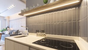 A modern kitchen with a sleek black induction cooktop, a white countertop, and a grey tiled backsplash. - Renovated 2BR in Recoleta | Balcony & Smart Lock (Recoleta)