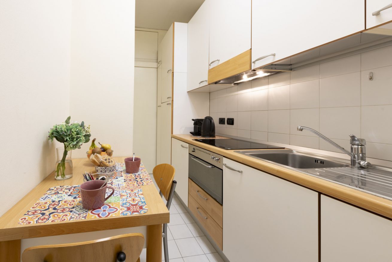 A compact kitchen with a wooden countertop, a stainless steel sink, and a built-in oven.