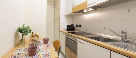 Una cocina compacta con encimera de madera, pileta de acero inoxidable y horno empotrado.