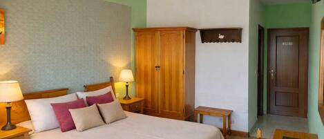 Une chambre d’hôtel comprenant un lit, des tables de chevet, une armoire, une petite table et une chaise.