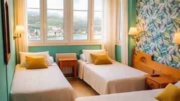 Habitación de hotel con dos camas, vista al mar y un mural floral.