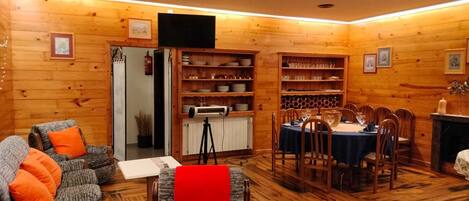 Interior acogedor de una cabaña con comedor, paredes de madera y chimenea.