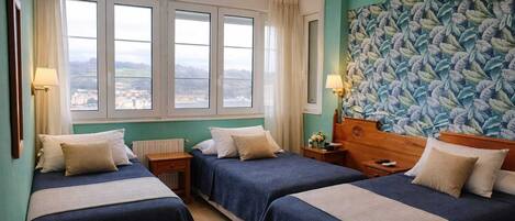Ein Hotelzimmer mit zwei Betten, einem großen Fenster und einem Blick sowie floralem Wandpapier.