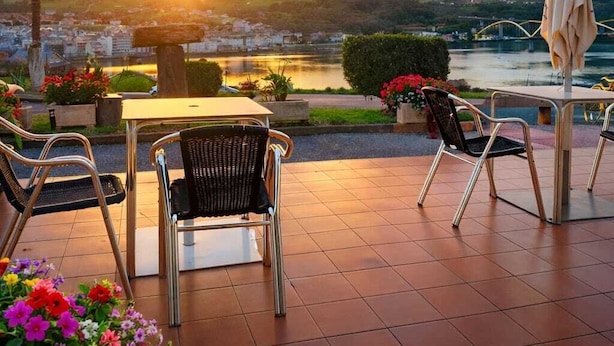Un patio al aire libre con una mesa y sillas, con vista a un río y un puente.
