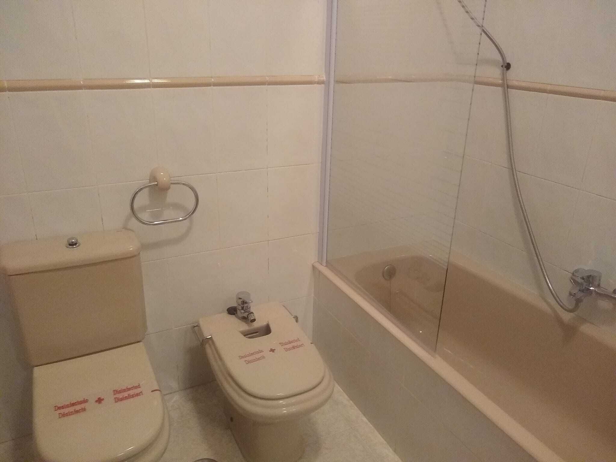Baño con dos inodoros, ducha y toallero.