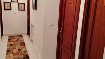 A hallway with a patterned carpet, wooden doors, and framed pictures on the wall.