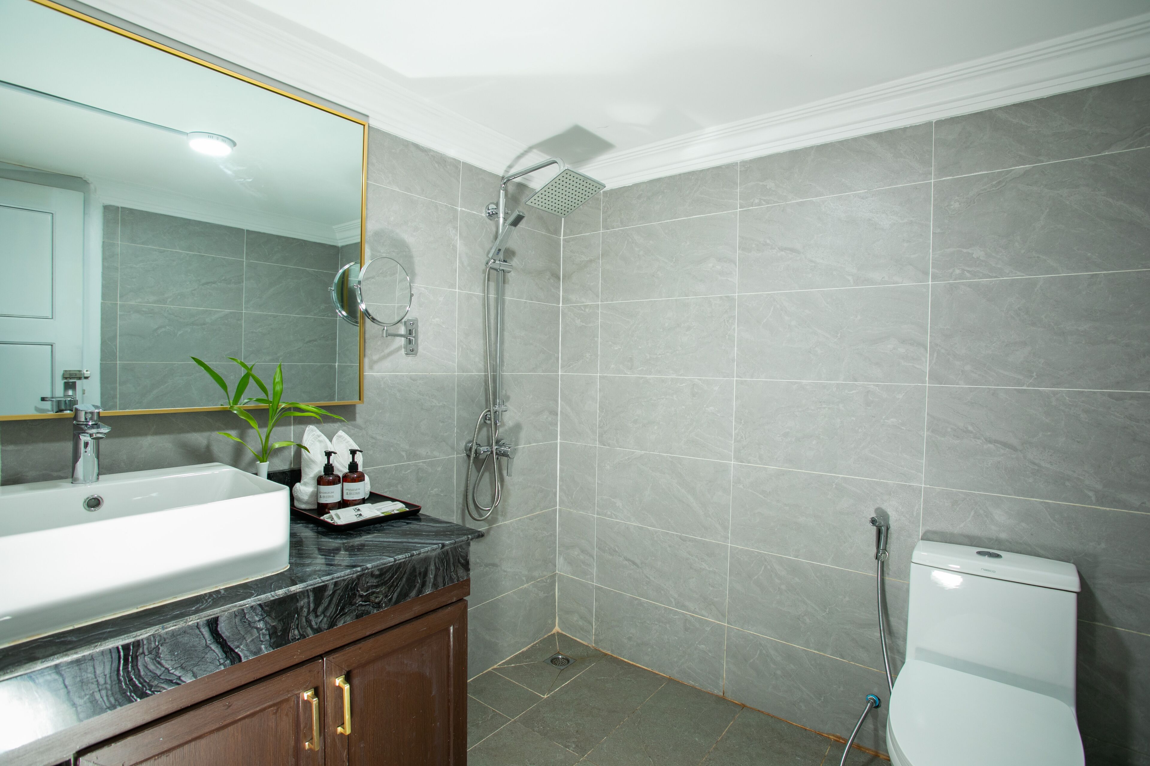 A bathroom with a sink, mirror, shower, and toilet.