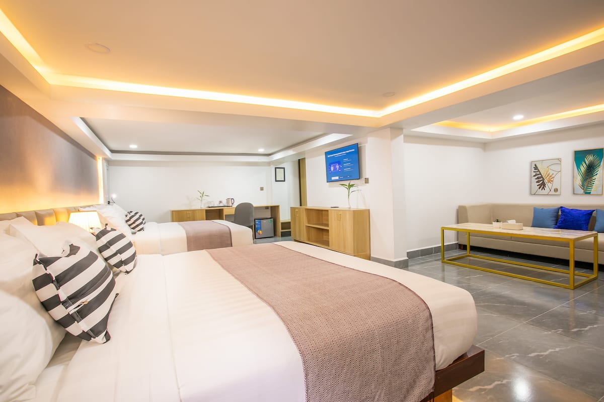 Ein modernes Hotelzimmer mit einem großen Bett, einem Schreibtisch, einer Couch und einem Fernseher.