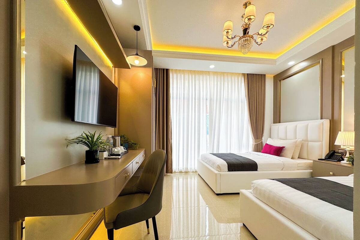 Ein Hotelzimmer mit Bett, Schreibtisch, Stuhl, Fernseher und einer Kristallleuchter.