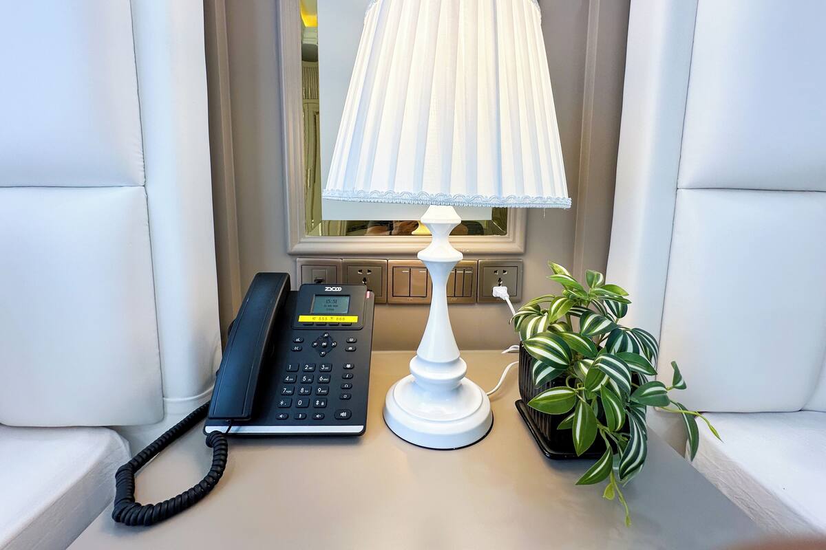 Ein Telefon, eine Lampe und eine Pflanze auf einem Tisch.