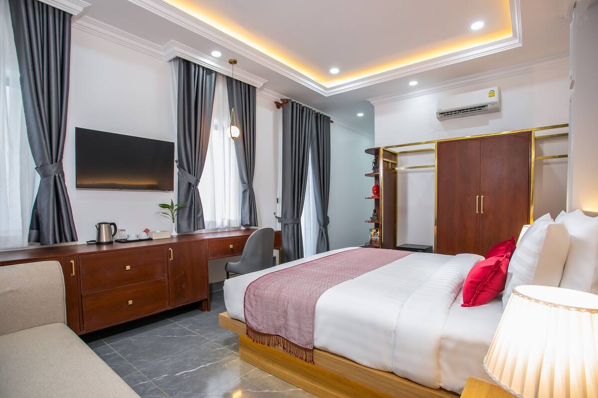 Ein modernes Hotelzimmer mit einem großen Bett, einem Schreibtisch, einem Sessel und einem Fernseher.