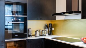 A modern kitchen with black cabinets, a Bosch oven, a coffee maker, and a toaster. - Aesthetic Artistry, by Veeve (Paris)